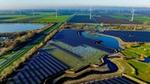Luftaufnahme eines großen Solarparks und eines Windparks zwischen Feldern und Seen