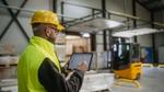Zwei Männer in weißen Laborkitteln und Schutzhelmen in einer Industrieanlage.